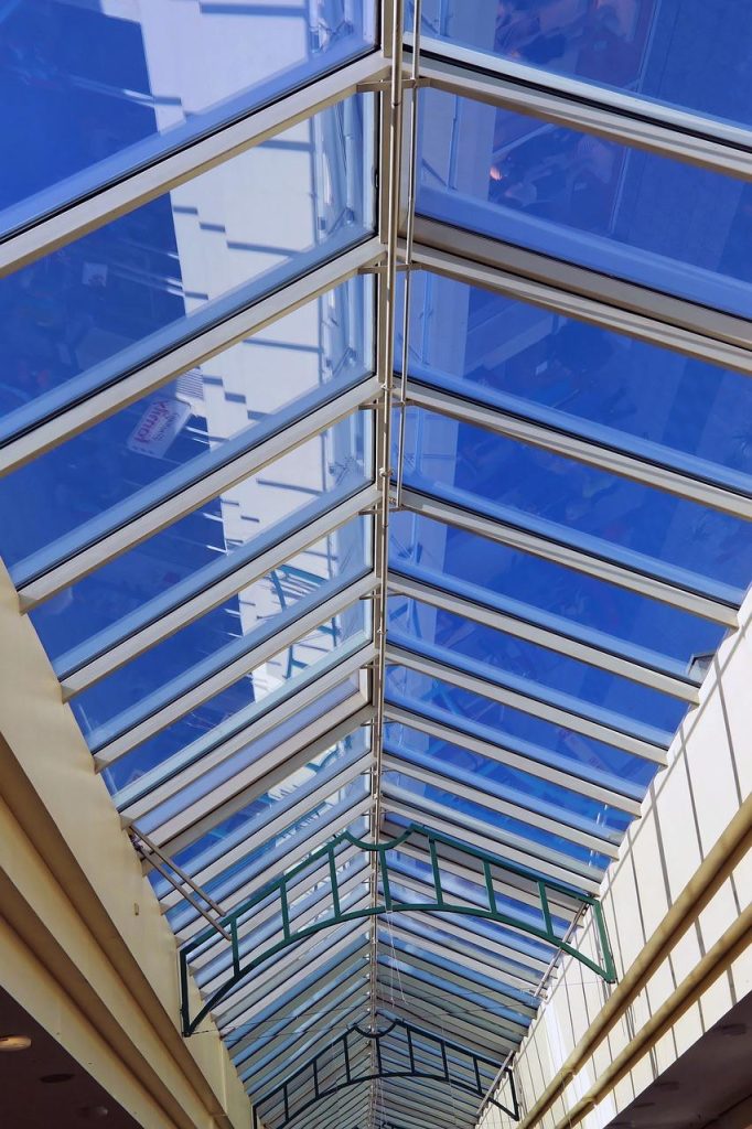 Moderne glazen overkapping tegen een huis met uitzicht op een groene tuin, creëert een naadloze overgang tussen binnen en bui